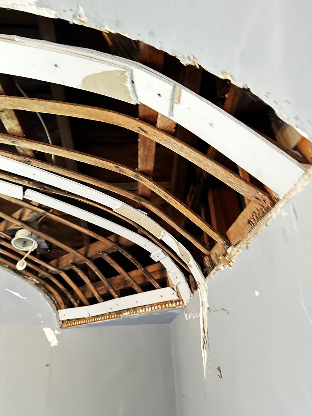 Curved vaulted ceiling opened up after water damage, exposing wood framing in Beverlywood, CA 90035