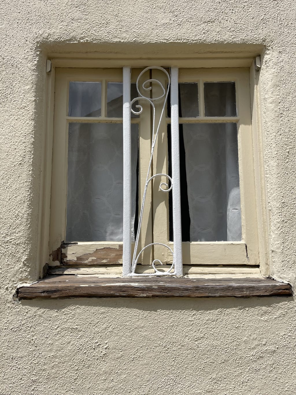 Cracked, peeling exterior wood sill on a small window before repair in Mid-City, CA 90036