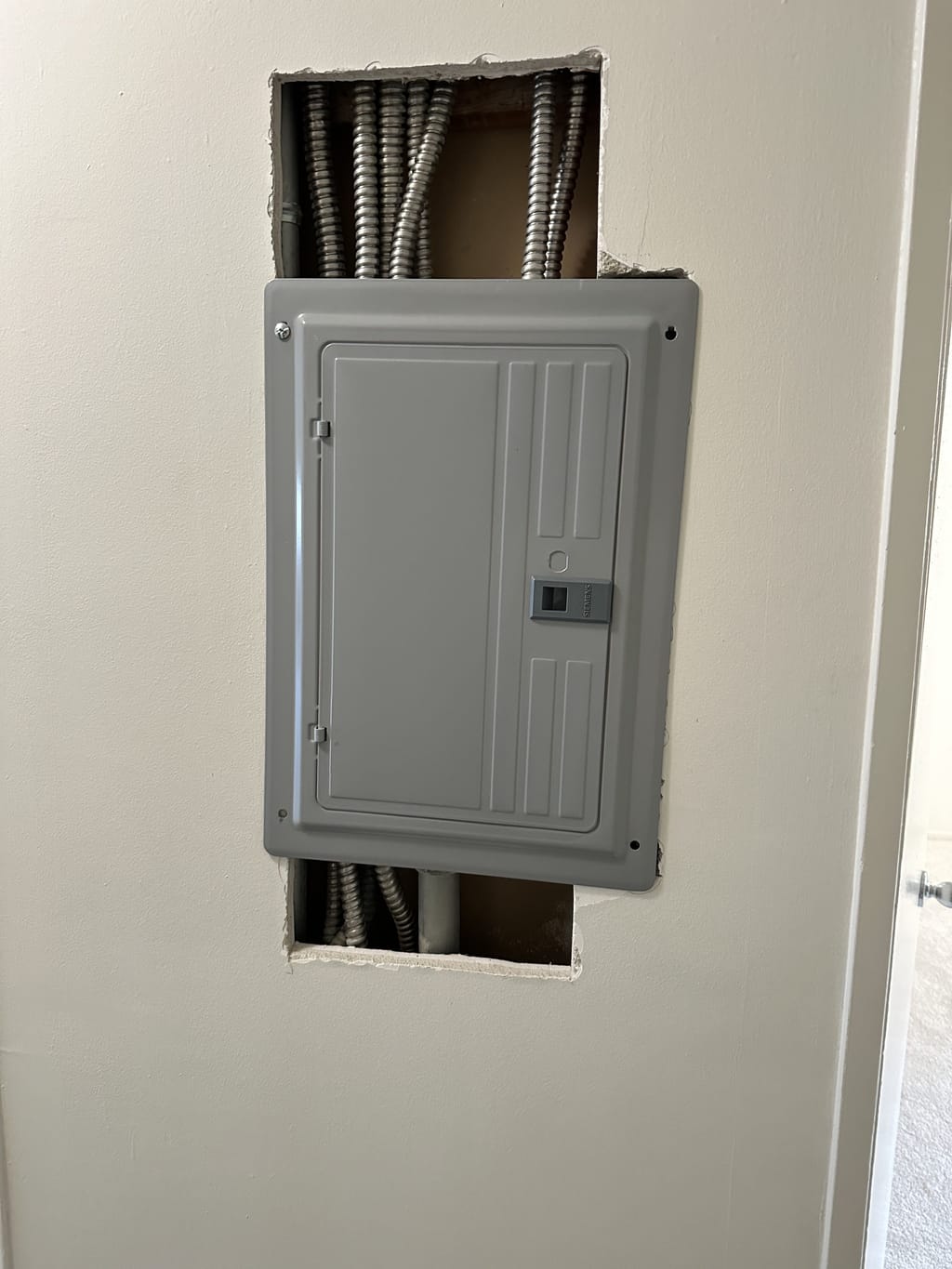 Drywall opened above and below an electrical panel exposing conduit in Ladera Heights, CA 90056