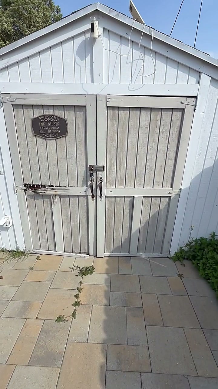 The whole shed front with faded paint and a broken door brace before repair in Hawthorne, CA 90250