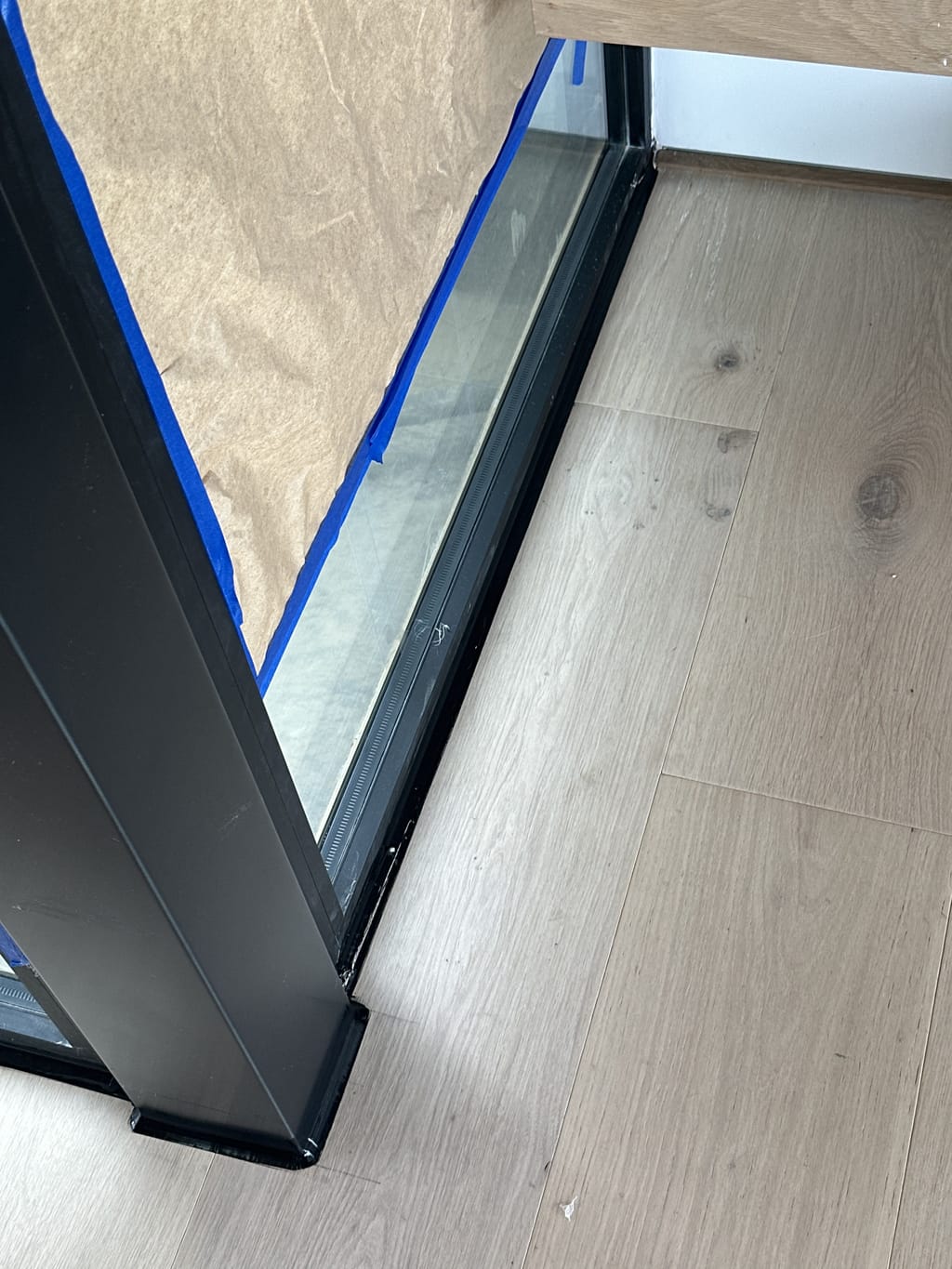 Black caulk line finished along a glass partition and wood floor in Malibu, CA 90265