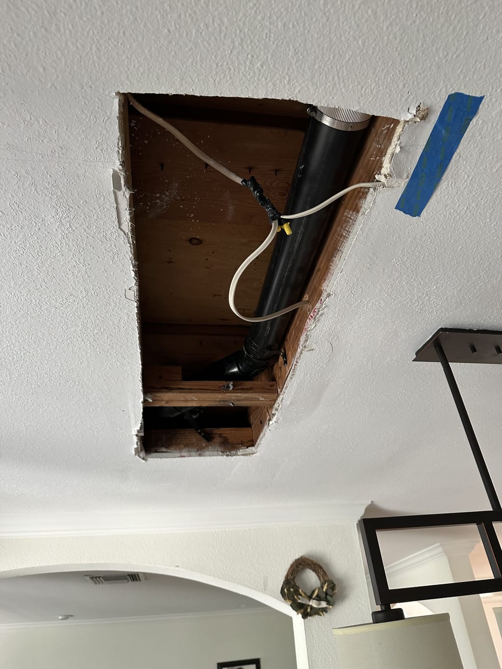 Ceiling hole opened over a dining room to reach plumbing in Encino, CA 91316