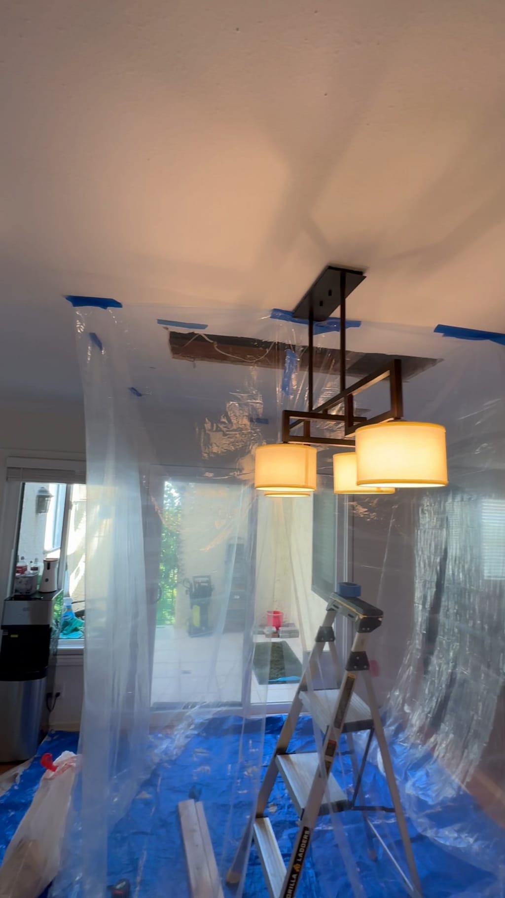 Dining room isolated with plastic sheeting while the ceiling opening is repaired around the chandelier in Encino, CA 91316