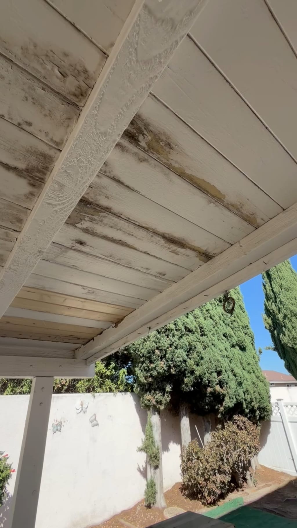 Leak-stained outdoor wood patio ceiling with a replaced raw plank before repainting in Irvine, CA 92618