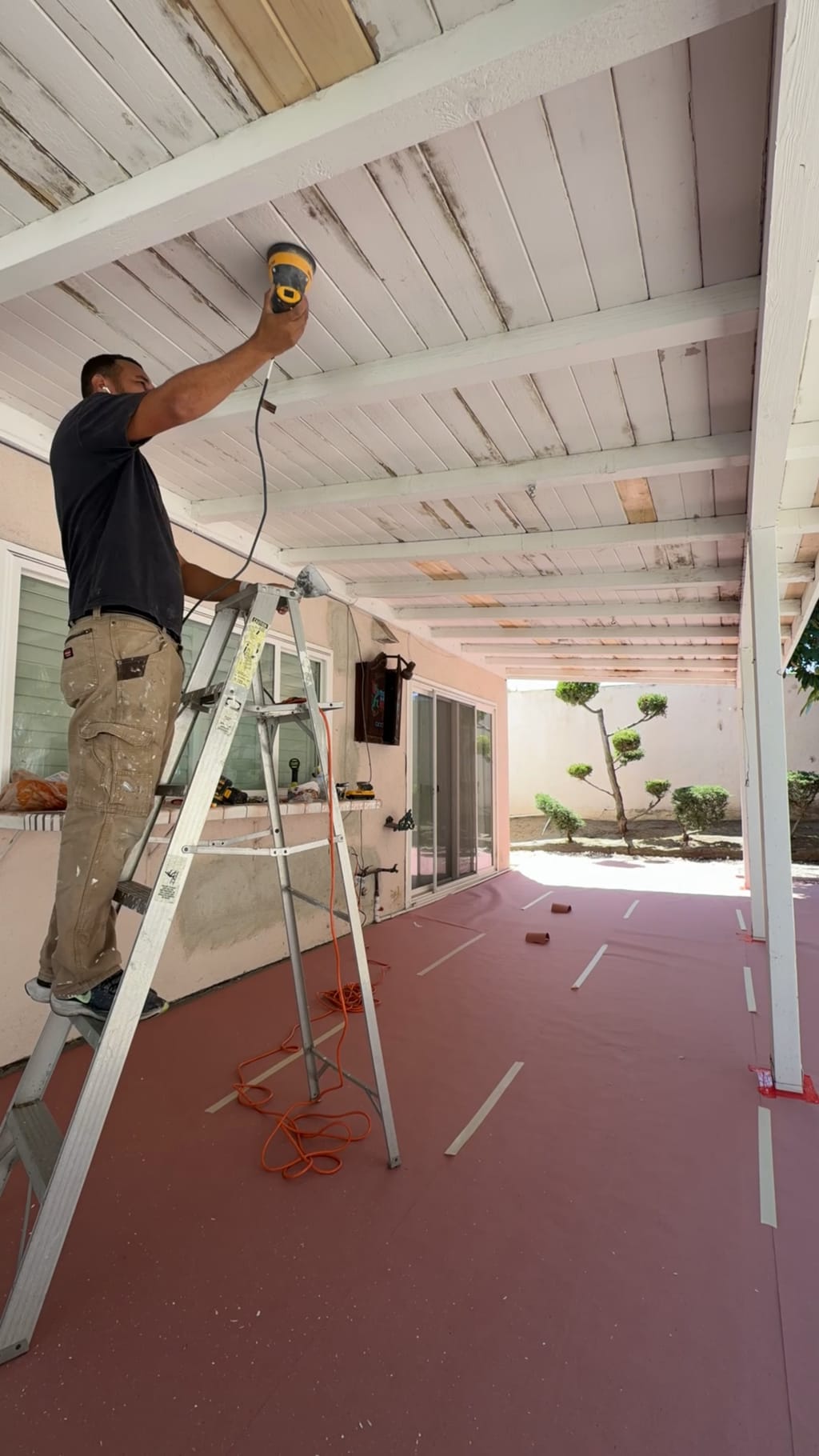 Eddie on a ladder sanding the patio wood ceiling in Irvine, CA 92618
