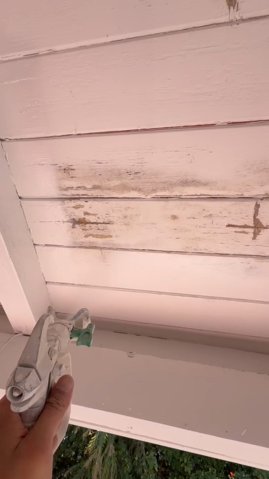 Spray gun repainting the wood patio ceiling planks in Irvine, CA 92618