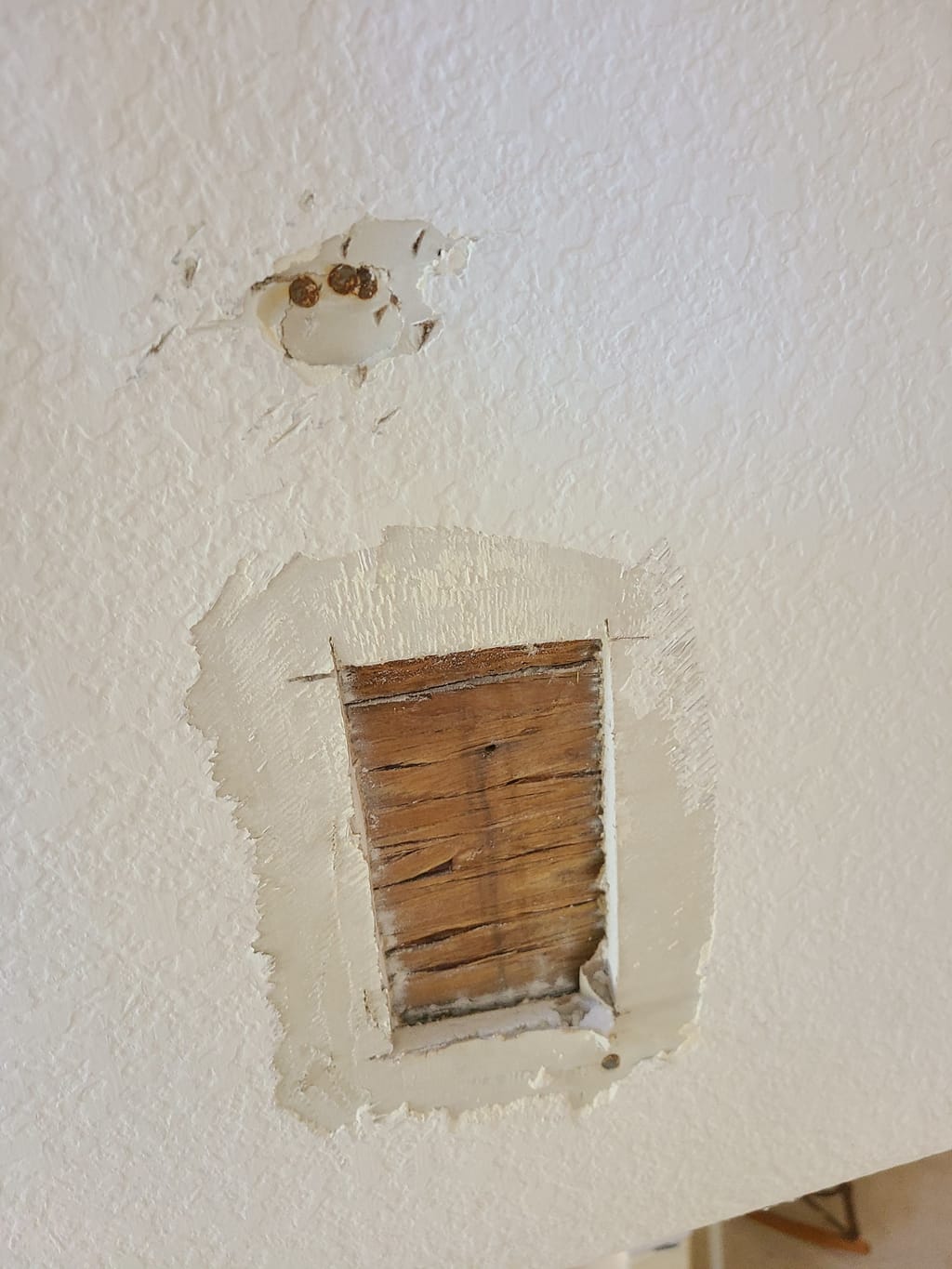 Second drywall hole near a sloped ceiling line before repair in Corona, CA 92882