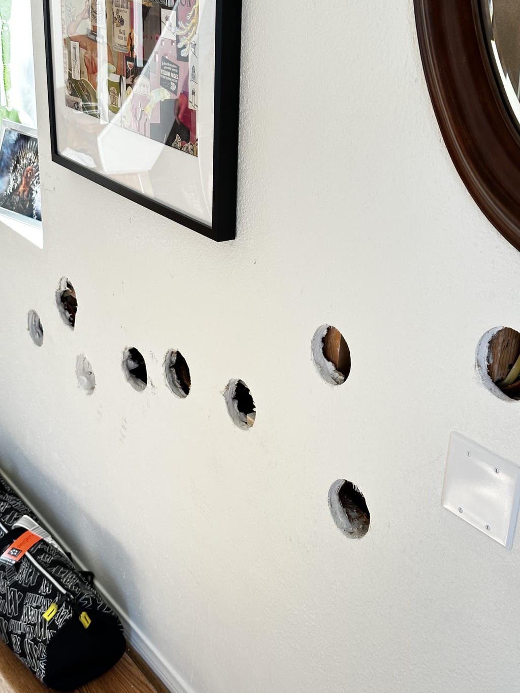 A row of round drywall access holes cut across a textured wall before repair in Venice, CA 90291